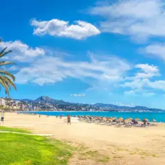Malaga w maju: słoneczna plaża z palmami, turkusowe morze i góry w tle. Idealna pogoda na wypoczynek.