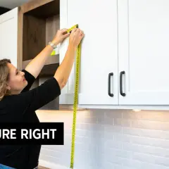 Woman demonstrating how to measure kitchen cabinets with a yellow tape measure. "Measure Right" text overlay.