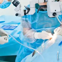 Chirurg wykonuje operację oka pod mikroskopem, używając precyzyjnych narzędzi.