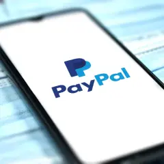 Telefon z logo PayPal na ekranie, leżący na niebieskich maseczkach. Chcesz wiedzieć, jak usunąć PayPal?