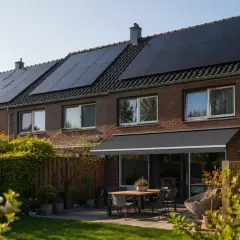 Reihenhaus mit vielen solar auf dem dach. Ein Garten mit Tisch und Stühlen lädt zum Verweilen ein.