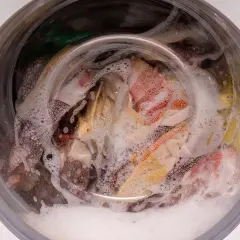 Kolorowe tkaniny, w tym mikrofibry, wirują w bąbelkach piany w pralce.