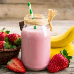 Pyszny koktajl truskawkowo bananowy w słoiku, obok świeże owoce i słomka. Idealny na orzeźwienie!
