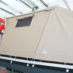 Tenda campeggio nautico su gommone, con oblò e salvagente arancione.