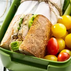 Pyszna kanapka z kurczakiem, świeże pomidorki i ogórek w zielonym pudełku na lunch.