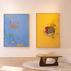 Two vibrant paintings, showcasing playful figures and abstract elements, exemplify modern art trends. A plush sofa and unique coffee table complete the stylish scene.