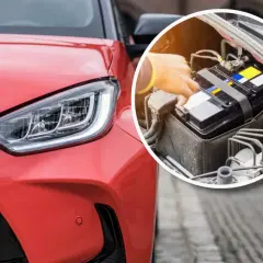 Czerwona Toyota hybryda nie chce odpalić. Widać reflektor i zbliżenie na akumulator, do którego ktoś dotyka.