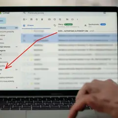 Laptop z otwartym mailem Gmail, zaznaczony folder "Spam" i czerwona strzałka wskazująca na temat maila "ESTA - AUTORYZACJA PODÓŻY USA".