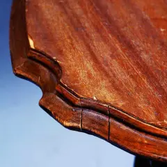 Gros plan sur le bord d'une table en bois qui se fissure, révélant les signes du temps et de l'usure.