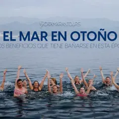 Grupo de personas nadando en el mar con los brazos en alto, disfrutando de los beneficios de bañarse en otoño.