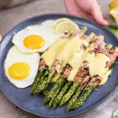 Pyszne szparagi z boczkiem i jajkiem sadzonym, polane sosem. Idealne śniadanie lub brunch.