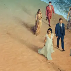 En grupp människor i eleganta kläder på en strand. Kanske är de det perfekta paret, eller så döljer de en hemlighet.
