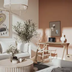 Ett ljust vardagsrum med en soffa, ett runt soffbord och ett skrivbord. Väggen bakom skrivbordet har samma färg som taket, en varm persikoton.