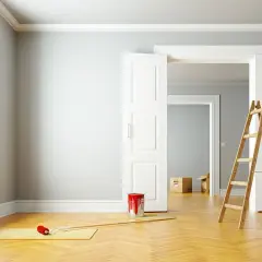 Leere Wohnung bereit zur Renovierung. Ein Farbeimer und eine Leiter stehen bereit, um die Wände zu streichen.