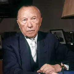 Konrad Adenauer, der von 1949 bis 1963 Bundeskanzler der Bundesrepublik Deutschland war, sitzt im Anzug am Schreibtisch.