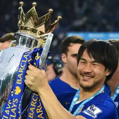 Shinji Okazaki z pucharem Premier League, uśmiechnięty, świętuje zwycięstwo.