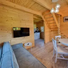 Przytulne wnętrze domku w stylu katy rybackie hotel. Drewniane ściany, kanapa, stół z krzesłami i schody na piętro.