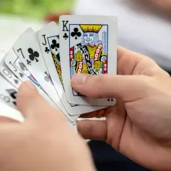 Ręce trzymają karty do gry, w tym króla karo. Czy to początek gry w oszusta?