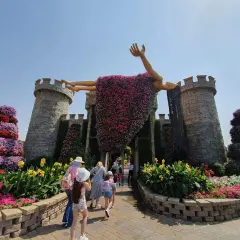 Niesamowity **Miracle Garden w Dubaju** zachwyca kwitnącą rzeźbą człowieka na tle zamku. Kolorowe kwiaty tworzą bajkową scenerię.