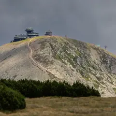 Kamienna ścieżka prowadzi na szczyt Śnieżki, gdzie widać budynki obserwatorium i kolejkę linową.