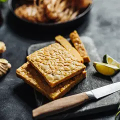 Pezzi di tempeh in agrodolce pronti per essere cucinati, con zenzero, lime e menta.