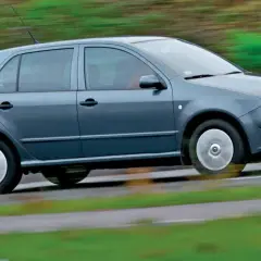 Szara Skoda Fabia 1 w ruchu, z rozmytym tłem zieleni i drogi.