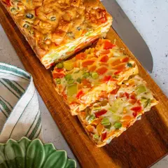 Tranches colorées d'une terrine de légumes savoureuse, garnie de poivrons, carottes et petits pois, prête à être dégustée.