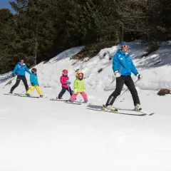 Maestro di sci guida bambini su piste innevate, un'ottima idea per dove sciare con bambini.