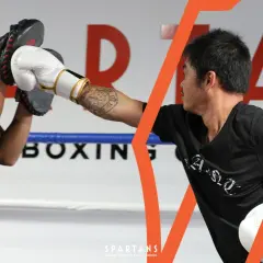 Two boxers train in a ring. One holds pads, the other throws a punch. Learn how to get better at boxing with focused drills.
