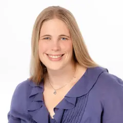 Lächelnde Frau mit blonden Haaren und blauen Augen, trägt eine lila Bluse. Sie könnte eine engagierte studentische Hilfskraft sein.