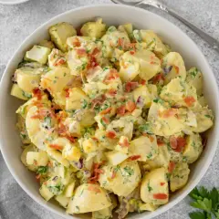Deliciosa ensalada de patata cremosa con trozos de huevo duro, tocino crujiente y perejil fresco.