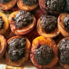 Deliziose pesche ripiene al forno, con un ripieno scuro e invitante, pronte per essere gustate.