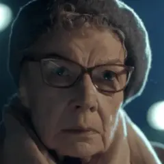 Aleksandra Górska w okularach i czapce, zamyślona, w świetle latarni.
