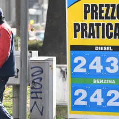 Prezzo praticato per la benzina: 2,429 €/litro. Un uomo in divisa osserva il cartello.