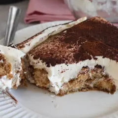 Fetta di tiramisù con abbondante crema al mascarpone 500 g, cosparsa di cacao amaro.