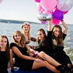 Uśmiechnięte kobiety na łodzi z balonami świętują wieczór panieński.