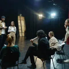 Aktorzy i reżyser dyskutują na scenie, przygotowując się do spektaklu.