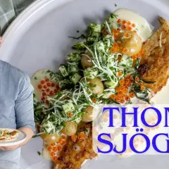 En glad man presenterar en tallrik med panerad torsk, små potatisar, gurka, dill och romsås.