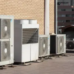 Rząd jednostek zewnętrznych klimatyzacji i pomp ciepła na dachu. Pomaga to zrozumieć, jak obliczyć potrzebną moc pompy ciepła.