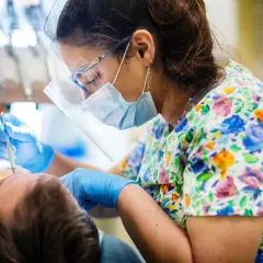 Dentystka w maseczce i okularach ochronnych wykonuje zabieg podniesienia dna zatoki szczękowej.