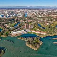 Marghera: cosa vedere? Un'area verde con canali, edifici storici e la città sullo sfondo.