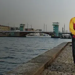 Kurier DHL z wózkiem pełnym paczek obok żółtego vana. Czy u kuriera DHL można płacić kartą? Tak, często jest to możliwe.