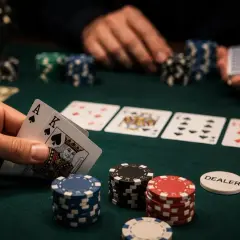 Gracz trzyma asa i króla, gotów do gry. Na stole leżą karty i żetony, a dealer czeka na ruch.