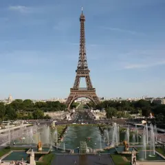 La Tour Eiffel se dresse fièrement, invitant à la découvrir. Des fontaines jaillissent, des gens se promènent, une belle journée pour monter à la Tour Eiffel.