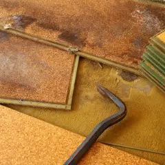 Beschädigter Laminatboden mit deutlichen Wasserflecken und einem Brecheisen. Die Korkunterlage ist aufgeweicht.