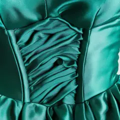 Szmaragdowa sukienka z marszczeniami i guzikiem. Materiał ma piękny, błyszczący kolor satyna, który dodaje jej elegancji.
