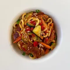 Szybki i tani obiad: makaron udon z kurczakiem, cukinią, marchewką i papryką, posypany sezamem.