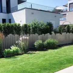 Moderne Zaunelemente bieten tolle **Sichtschutz Garten Ideen**. Ein gepflegter Rasen und üppige Pflanzen ergänzen die Architektur.