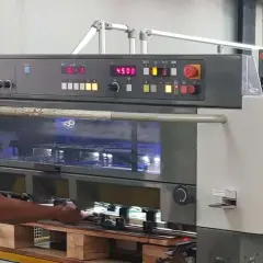 Operator w maszynie drukarskiej Komori Lithrone A37 z panelem sterowania i wyświetlaczem.