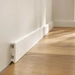 Battiscopa bianco moderno fissato con silicone, pronto per completare un pavimento in legno chiaro.